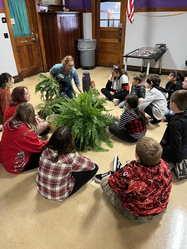 Students Sit on the Floor as an Instructor Talks About a Plant